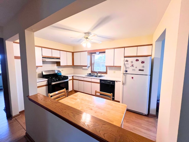 kitchen featuring light wood-type flooring, black dishwasher, white fridge, white cabinetry, and stainless steel range with gas stovetop