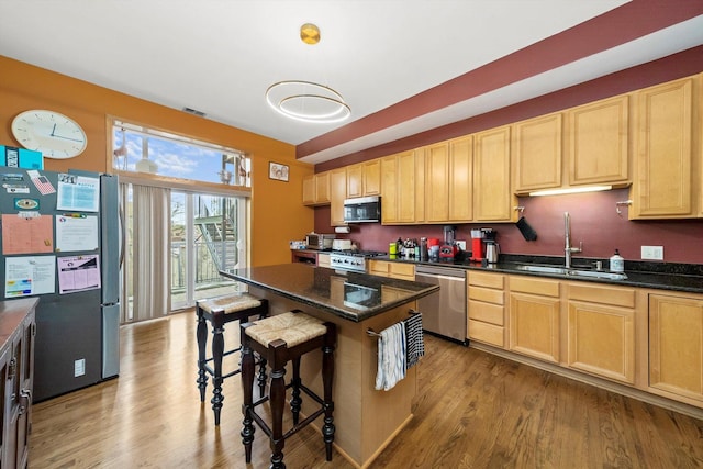 kitchen featuring light brown cabinets, sink, a breakfast bar area, light wood-type flooring, and stainless steel appliances