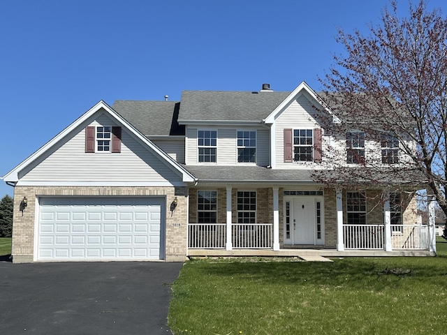 view of front of house with covered porch, a garage, and a front yard