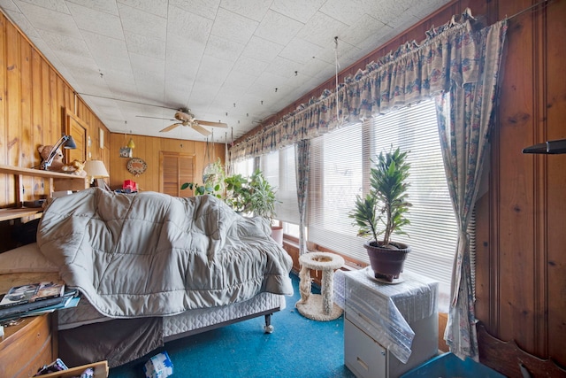 bedroom featuring carpet floors, ceiling fan, and wood walls