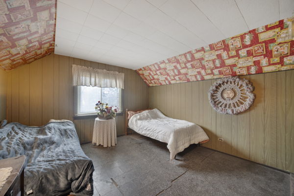 bedroom featuring wood walls and lofted ceiling