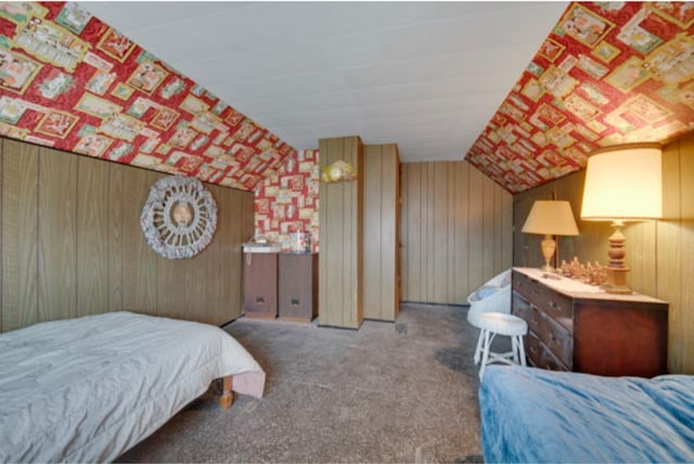 carpeted bedroom featuring vaulted ceiling and wood walls