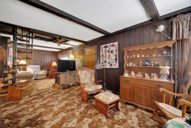 living room featuring ceiling fan, wooden walls, and beamed ceiling