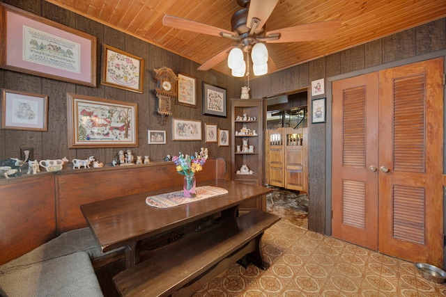 dining room with wooden walls, ceiling fan, and wood ceiling