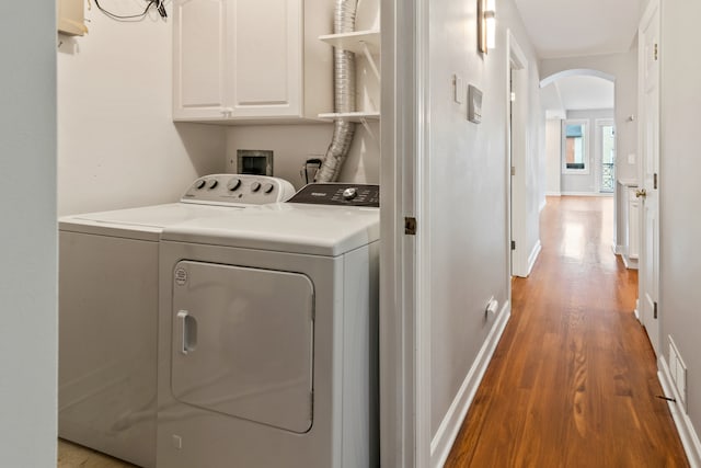 clothes washing area with hardwood / wood-style flooring, cabinets, and washing machine and clothes dryer