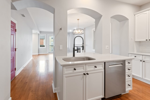 kitchen with white cabinetry, sink, an inviting chandelier, light hardwood / wood-style flooring, and decorative backsplash