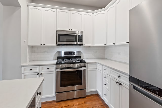 kitchen with white cabinets, backsplash, stainless steel appliances, and light hardwood / wood-style flooring