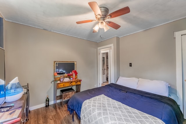 bedroom with ceiling fan, crown molding, and wood-type flooring