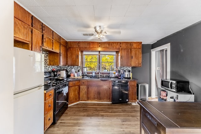 kitchen featuring tasteful backsplash, ceiling fan, dark wood-type flooring, sink, and black appliances