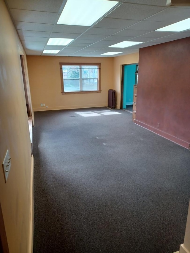 carpeted spare room with baseboards and a drop ceiling