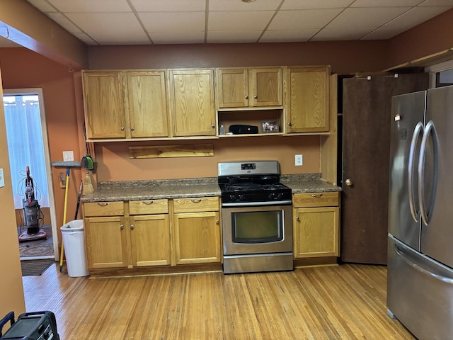 kitchen featuring stainless steel appliances, light hardwood / wood-style floors, and dark stone countertops