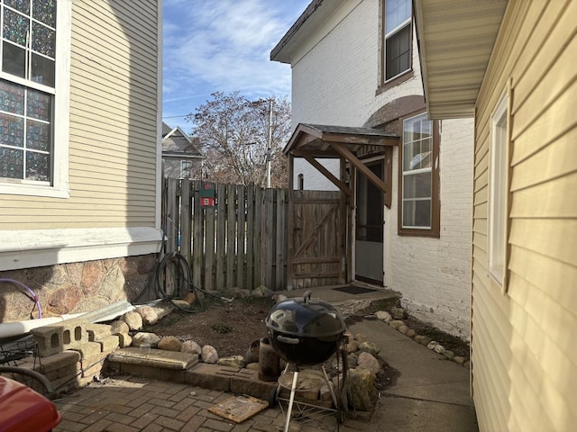 view of side of home with brick siding, fence, and a patio area