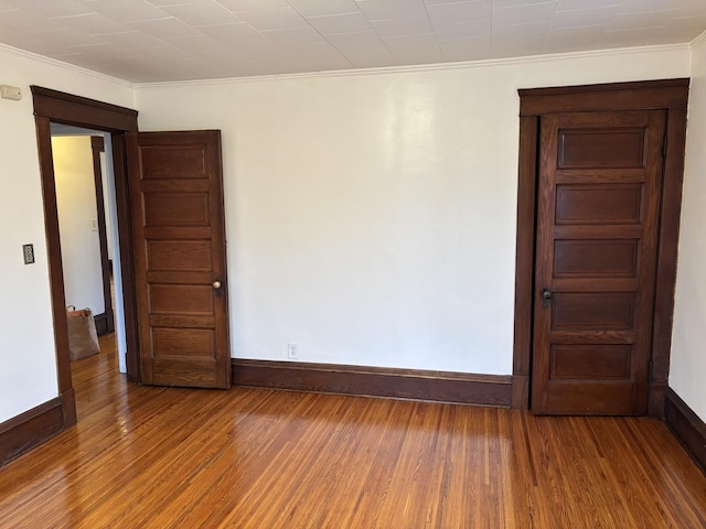 unfurnished room with baseboards, ornamental molding, and wood finished floors