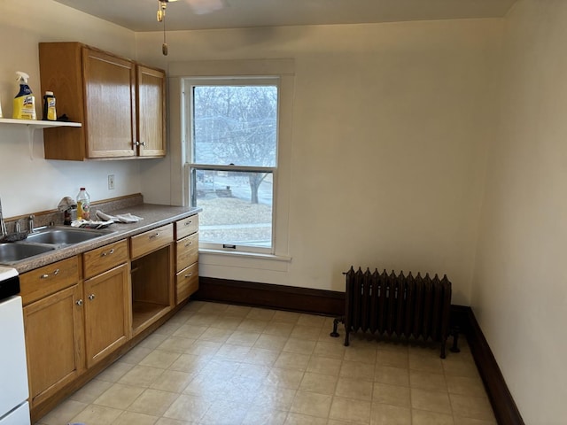 kitchen featuring open shelves, a sink, radiator heating unit, and a healthy amount of sunlight