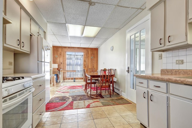 kitchen with white cabinets, white range oven, a paneled ceiling, decorative backsplash, and light tile patterned floors