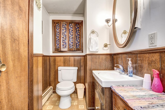 bathroom featuring a baseboard radiator, a textured ceiling, toilet, wooden walls, and vanity