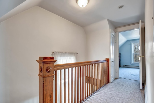 hallway with light carpet, vaulted ceiling, and a baseboard heating unit