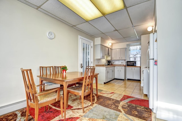 dining area featuring a paneled ceiling, sink, light tile patterned floors, and a baseboard radiator