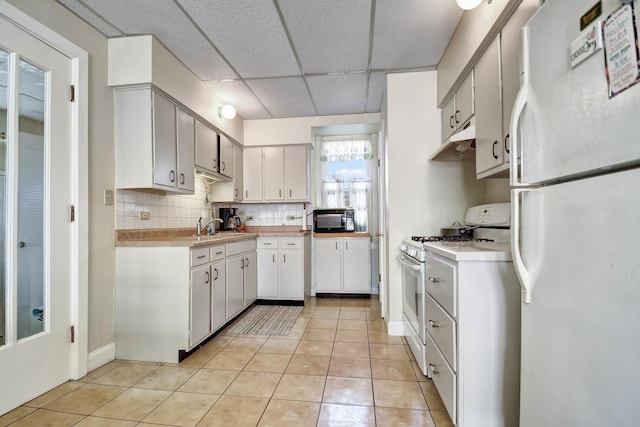 kitchen with white cabinetry, a drop ceiling, white appliances, decorative backsplash, and light tile patterned flooring