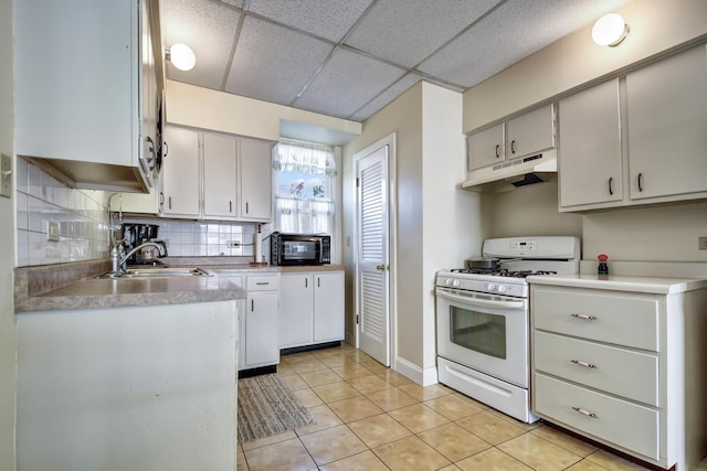 kitchen featuring a paneled ceiling, backsplash, sink, light tile patterned floors, and gas range gas stove