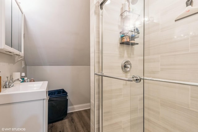 bathroom with a shower with door, vanity, lofted ceiling, and hardwood / wood-style flooring