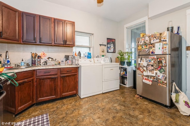 kitchen with decorative backsplash, sink, stainless steel refrigerator, and washing machine and clothes dryer