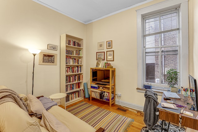 office area with light hardwood / wood-style floors and ornamental molding