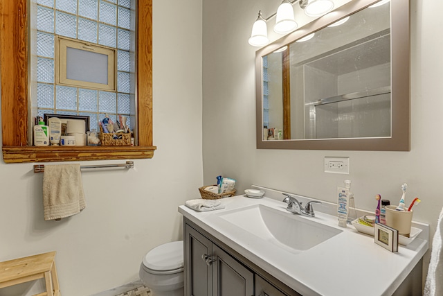 bathroom with toilet, a healthy amount of sunlight, an enclosed shower, and vanity