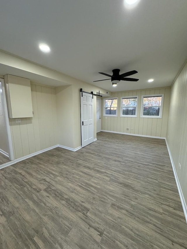 empty room featuring a barn door, hardwood / wood-style flooring, and ceiling fan