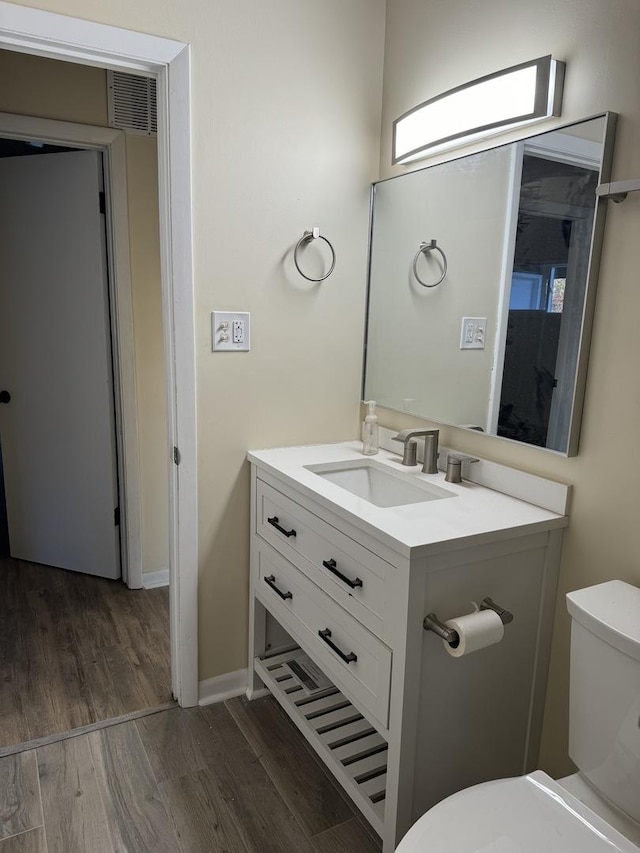 bathroom featuring toilet, vanity, and hardwood / wood-style flooring