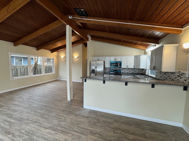 kitchen with kitchen peninsula, decorative backsplash, dark hardwood / wood-style flooring, and stainless steel appliances