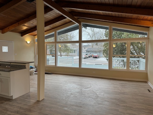 unfurnished living room with vaulted ceiling with beams, wood ceiling, and light wood-type flooring