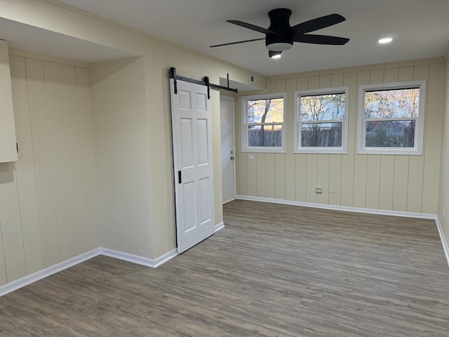 spare room with a barn door, wood-type flooring, and a wealth of natural light