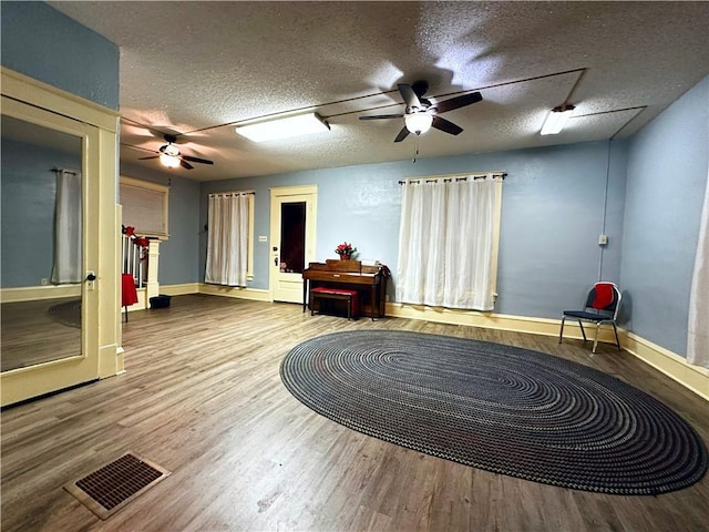 sitting room featuring hardwood / wood-style flooring, ceiling fan, and a textured ceiling