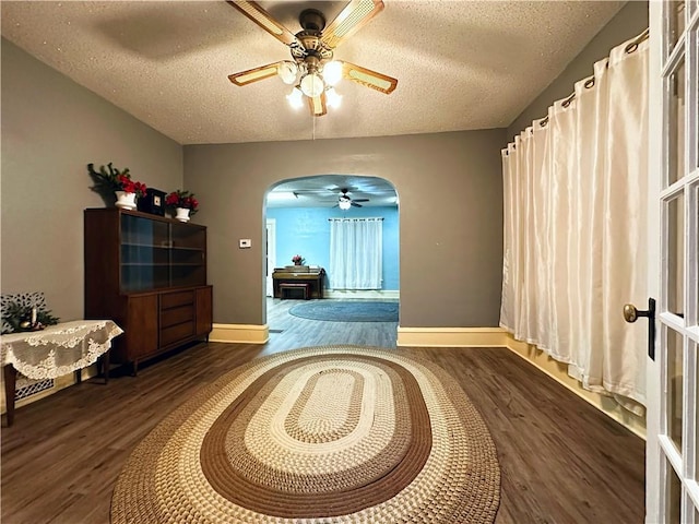 interior space with ceiling fan, dark hardwood / wood-style floors, and a textured ceiling