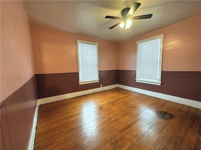 spare room featuring hardwood / wood-style flooring, ceiling fan, and wooden walls