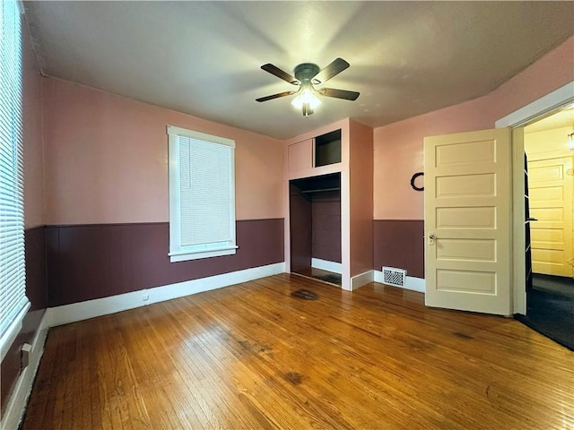 unfurnished bedroom featuring hardwood / wood-style floors, ceiling fan, and a closet