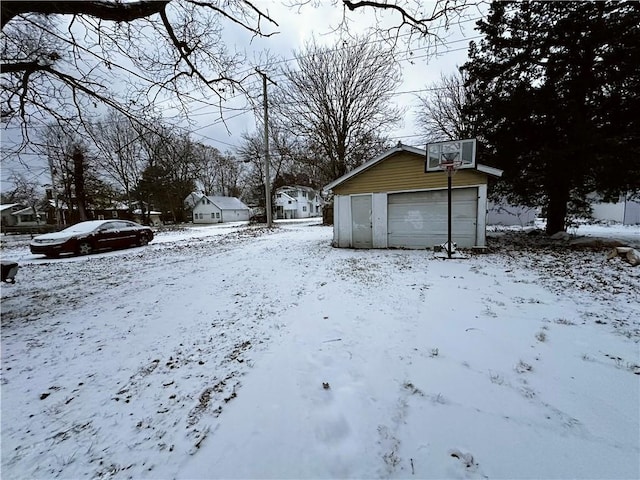 yard layered in snow featuring a garage and an outdoor structure