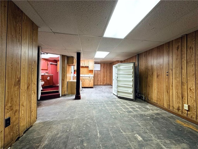 basement with a drop ceiling and wooden walls