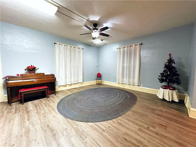 living area featuring ceiling fan, hardwood / wood-style floors, and a textured ceiling