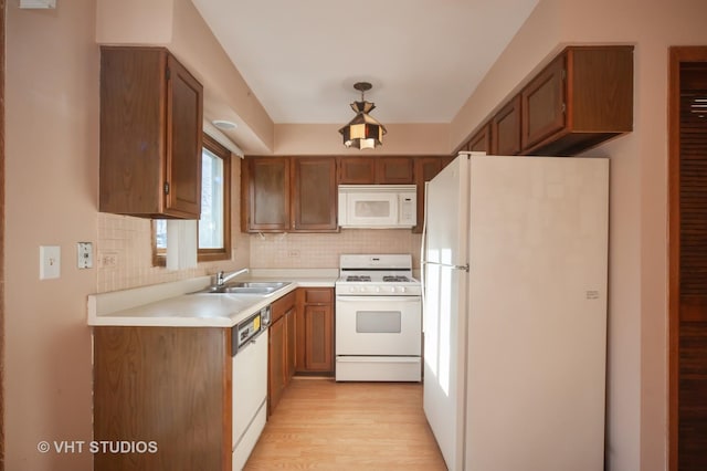 kitchen featuring white appliances, backsplash, light hardwood / wood-style flooring, and sink