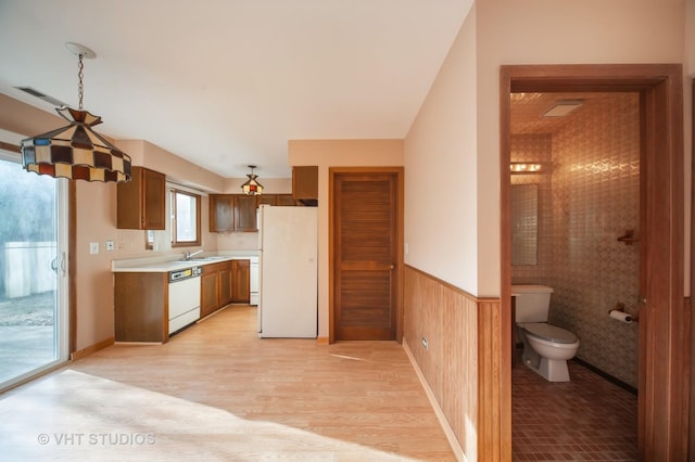 kitchen with white appliances, light hardwood / wood-style floors, and wood walls