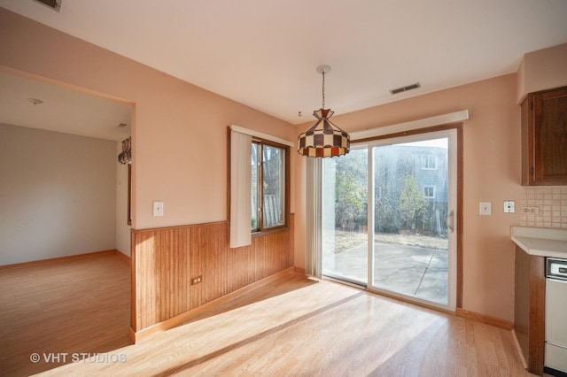 unfurnished dining area with light hardwood / wood-style flooring and wood walls