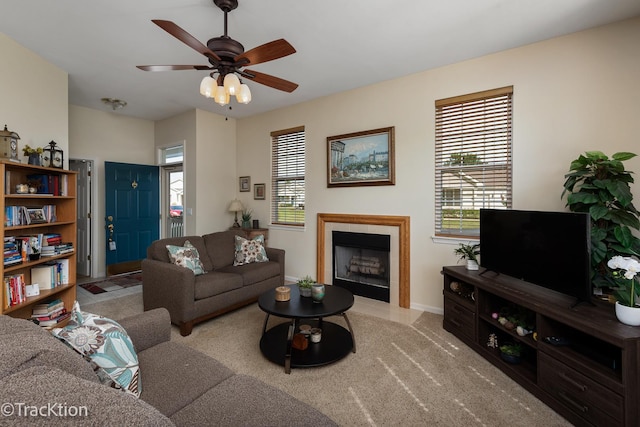 living room with a wealth of natural light, baseboards, a ceiling fan, and a tiled fireplace