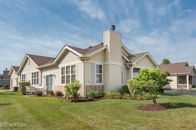 exterior space featuring roof with shingles, a chimney, a lawn, and brick siding