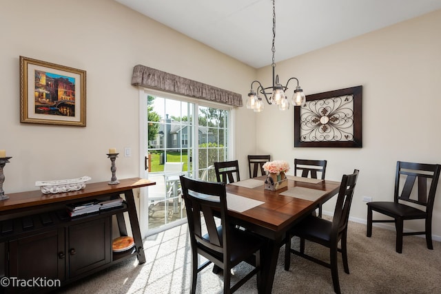 dining space featuring light carpet, a notable chandelier, and baseboards