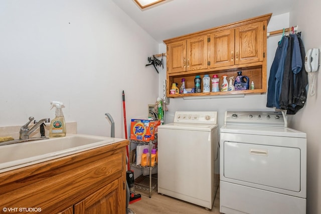 laundry area featuring washing machine and dryer, light hardwood / wood-style flooring, cabinets, and sink