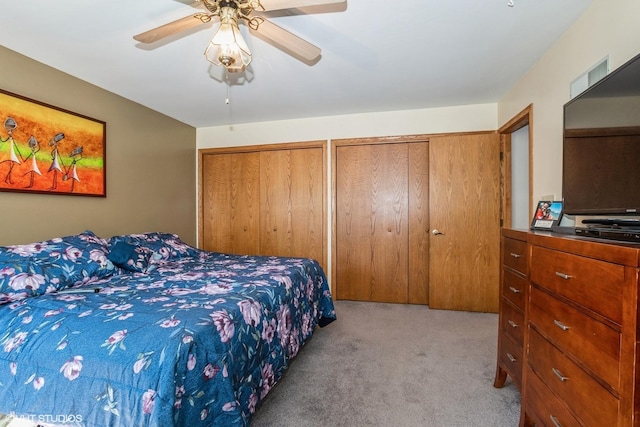 carpeted bedroom featuring ceiling fan and multiple closets