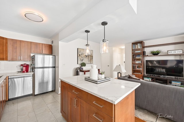 kitchen with light stone countertops, a center island, decorative light fixtures, decorative backsplash, and appliances with stainless steel finishes