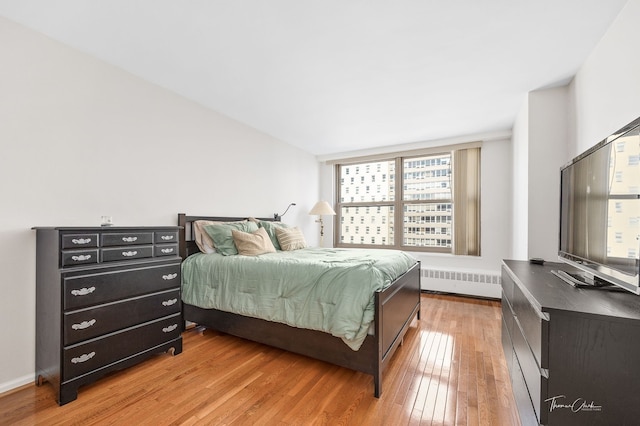 bedroom with radiator heating unit and hardwood / wood-style flooring